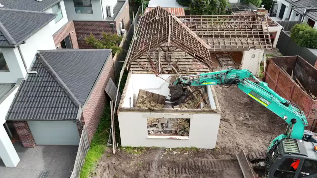 Close-up of a Demolition Masters branded skip bin viewed through fencing on a cleared site